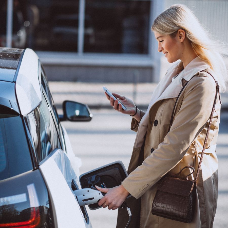 En kvinne lader elbilen sin