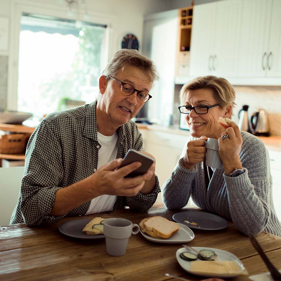 Et par sitter på kjøkkenet og ser på mobilen sammen