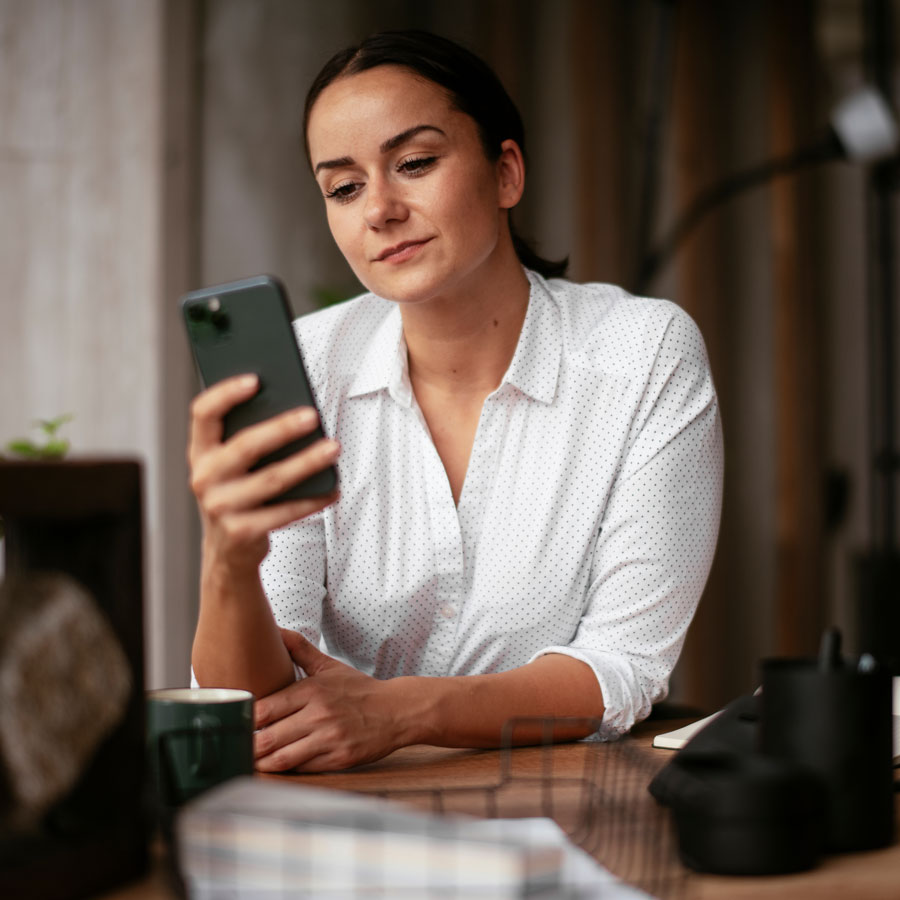 Bilde av en dame som ser på mobilen for å illustrere Fjordkraft sin side hvor du kan se hvilken strømavtale som passer best for deg.