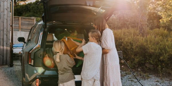 Familie pakker i bilen mens den lader