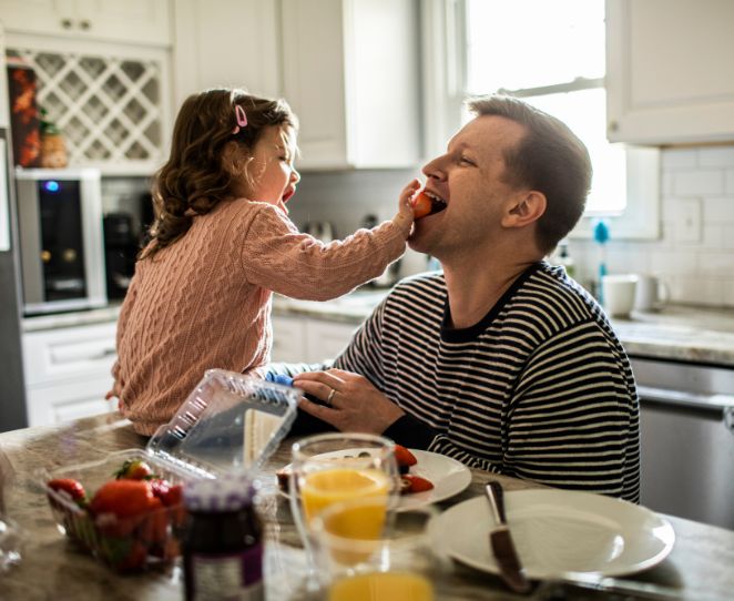En far sitter med datteren sin på kjøkkenet