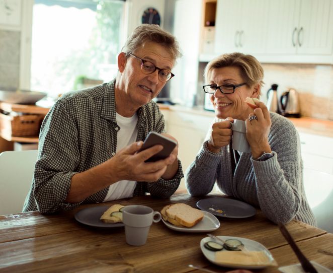 Et par ser på telefonen sammen på kjøkkenet