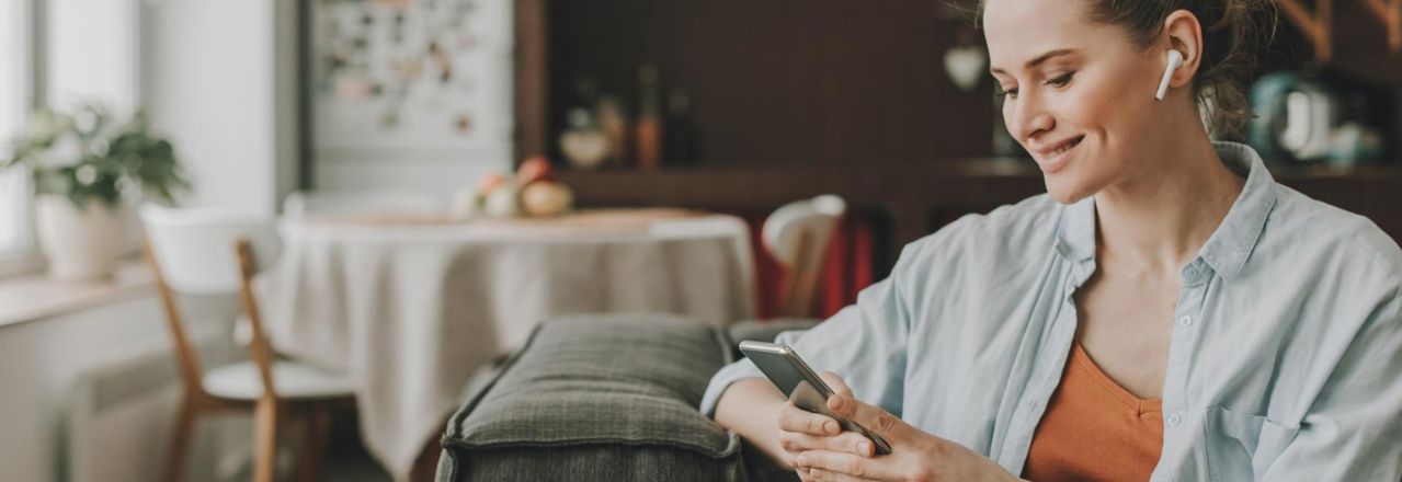 Kvinne bruker mobilen i stuen