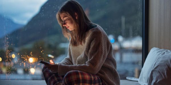 Ung kvinne bruker mobilen hjemme