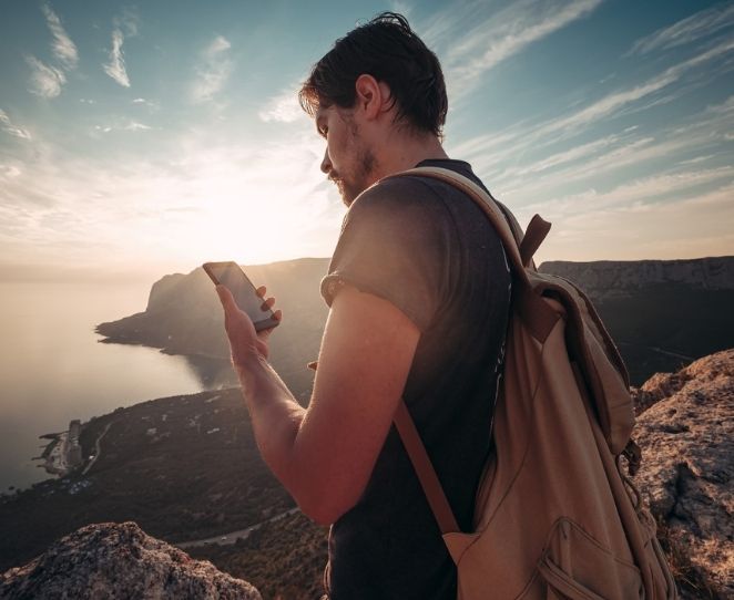 Mann på fjelltur med en mobiltelefon