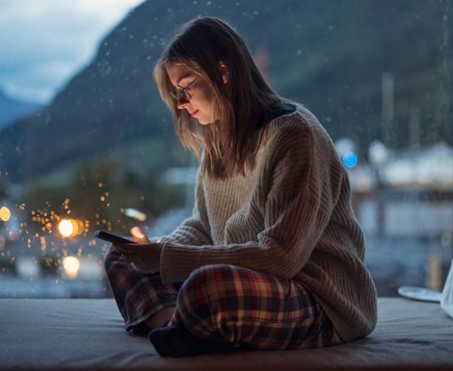 Ung kvinne bruker mobiltelefonen hjemme