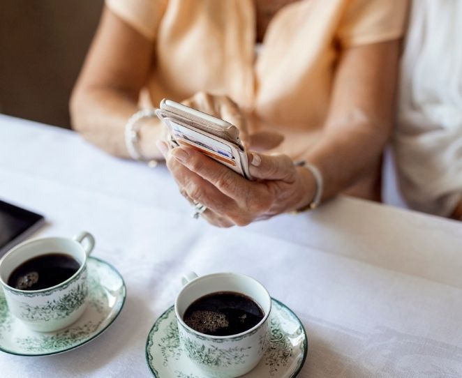 To personer ser på mobilen med hver sin kaffekopp