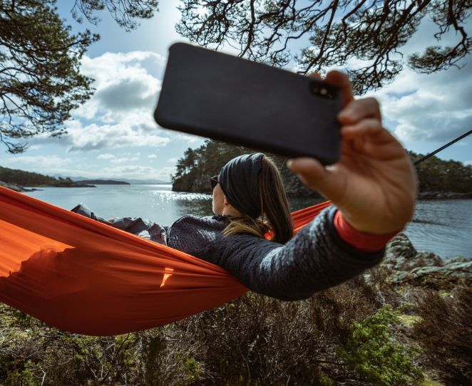 Kvinne tar bilde med mobilen i en hengekøye