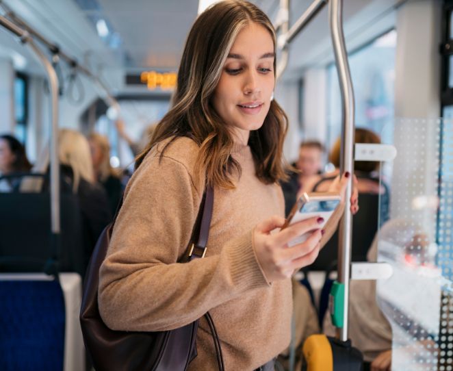 Kvinne sjekker mobilen sin på bussen
