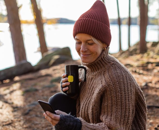 Kvinne på tur i skogen ser på telefonen sin