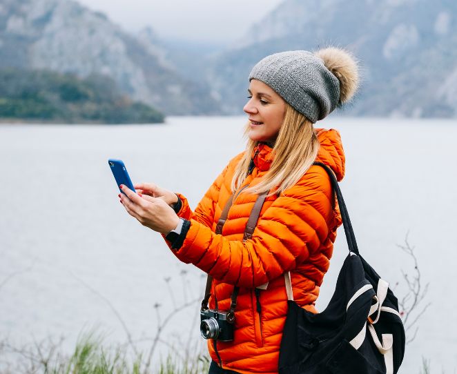 Kvinne bruker mobilen på tur i fjellet