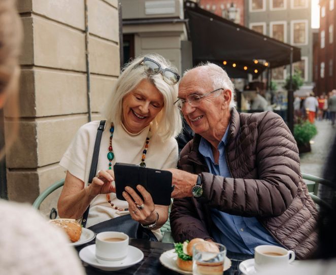 Et eldre par ser på en mobiltelefon sammen