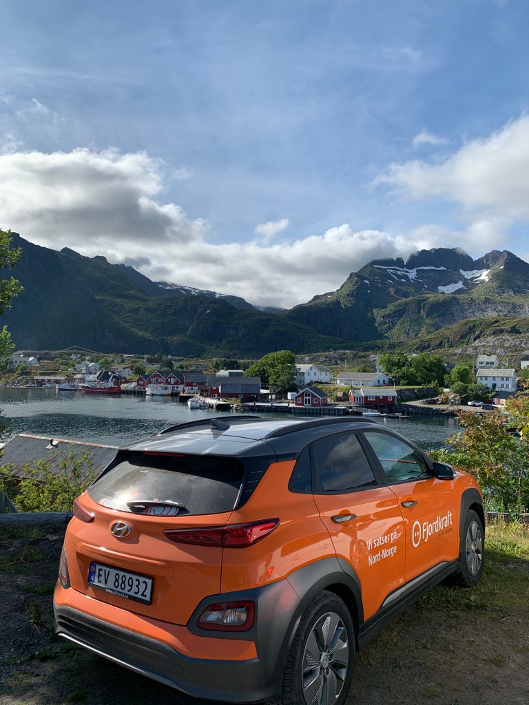 Fjordkrafts oransje elbil foran sjarmerende småhus i Lofoten